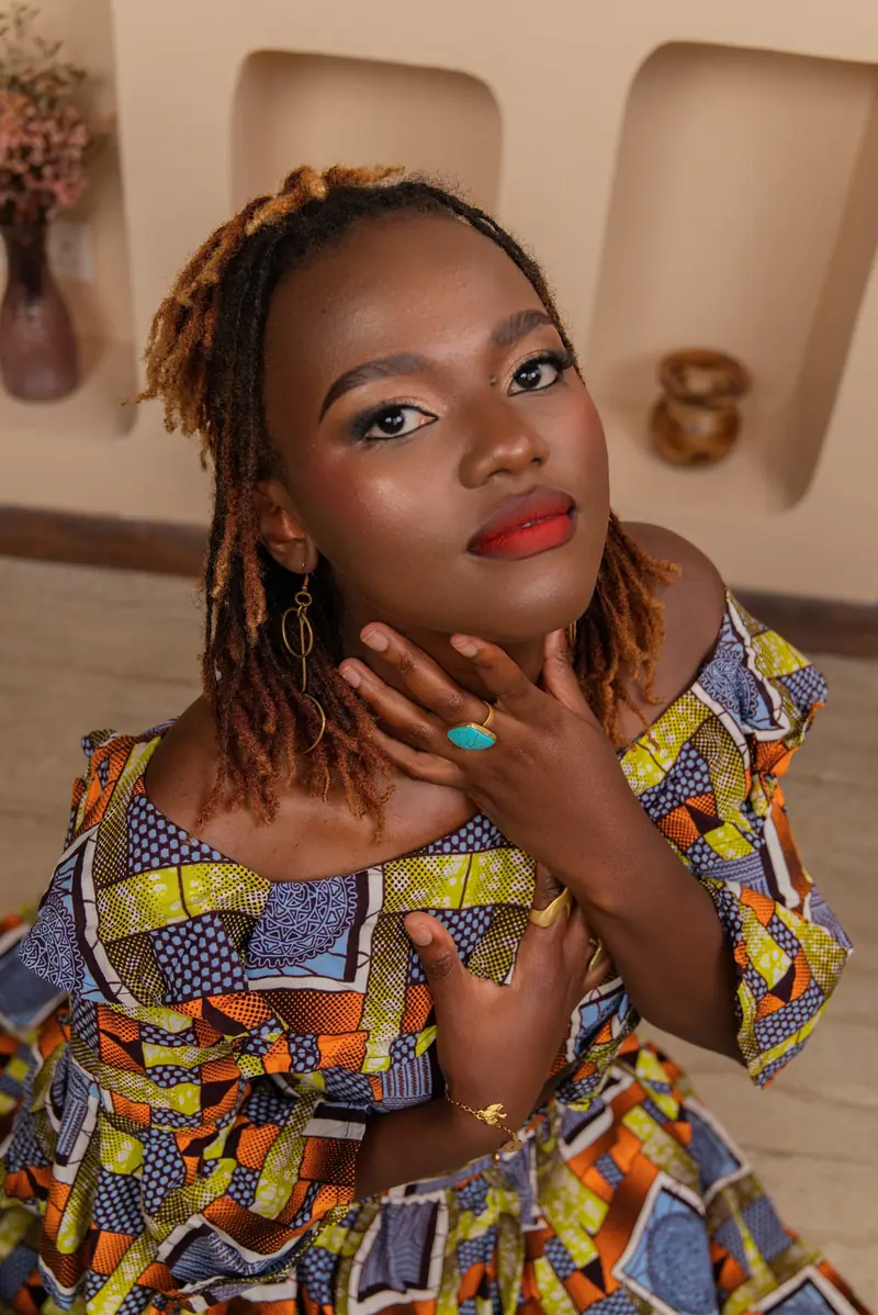 Woman in a bright wax-print top resting her chin on her hand