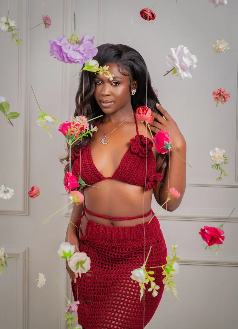 Woman in a red crochet set surrounded by hanging flowers